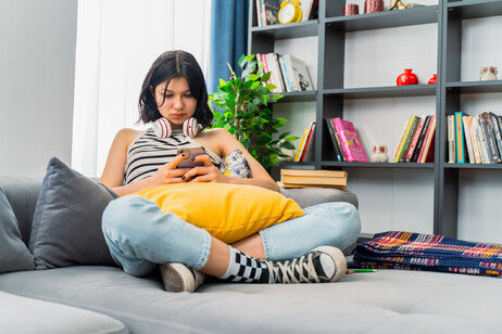 Un'adolescente controlla lo smartphone, foto iStock.